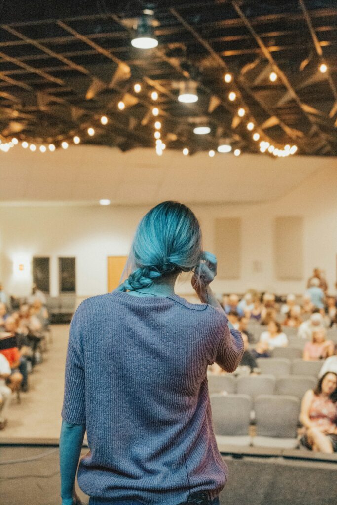 Image of a person presenting at a conference. The camera is from the back of them.